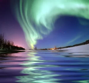 A vivid aurora borealis arches across the night sky over Bear Lake, Alaska, reflected in still water