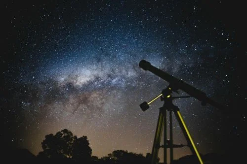 A black telescope pointed at a starry night sky, capturing the essence of stargazing on Astronomy Day.