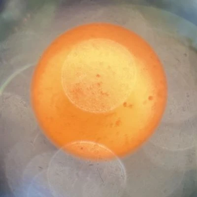 View of the sun through a telescope eyepiece, showing sunspots and lens reflections